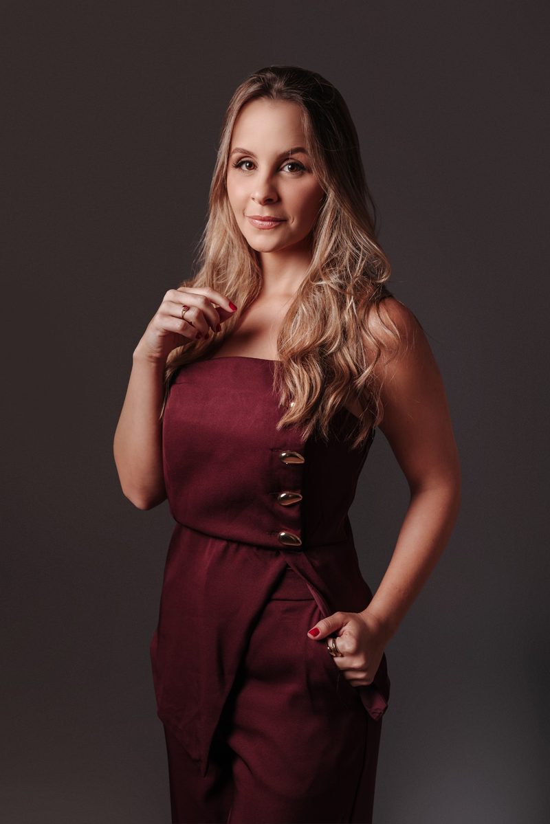 Mariana de Paula Araújo, advogada trabalhista, em retrato de meio corpo com vestido bordô de botões dourados.