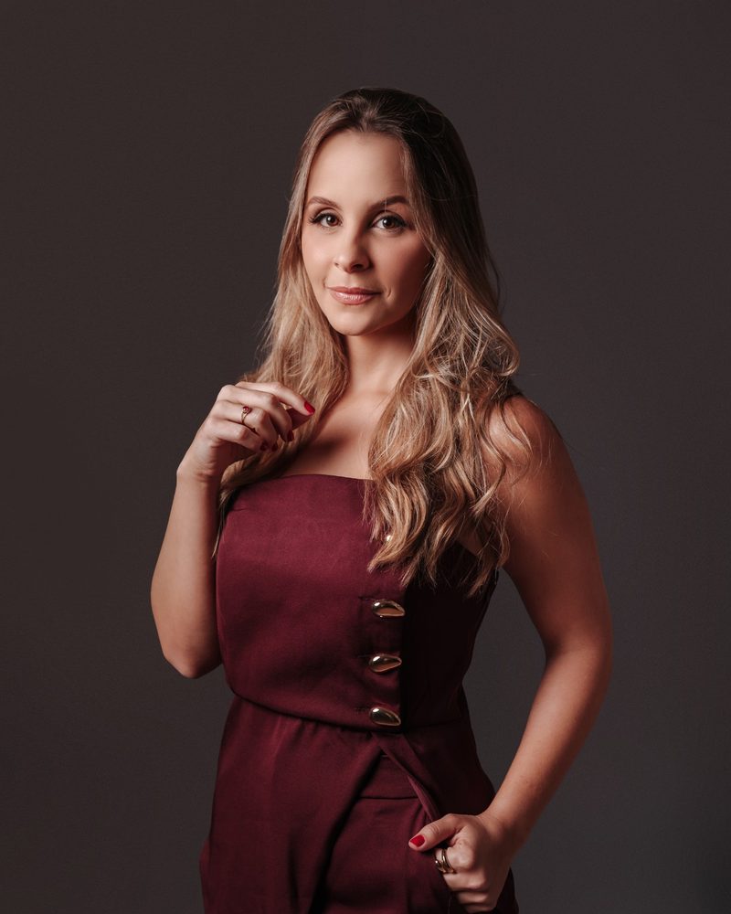 Mariana de Paula Araújo, advogada trabalhista, em retrato de meio corpo com vestido bordô de botões dourados.